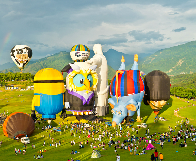 대만 타이동 국제 열기구 페스티벌, 초원 위에 여러 개의 열기구가 떠 있고 사람들이 모여 있는 모습