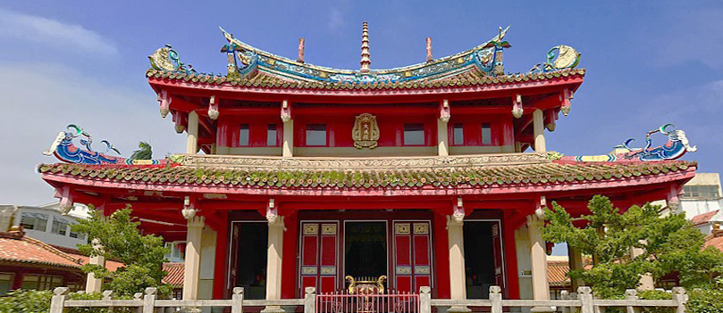 붉은 기둥과 지붕 장식이 화려한 대만 전통 사찰 건물, 푸른 하늘 아래 정면에서 본 모습